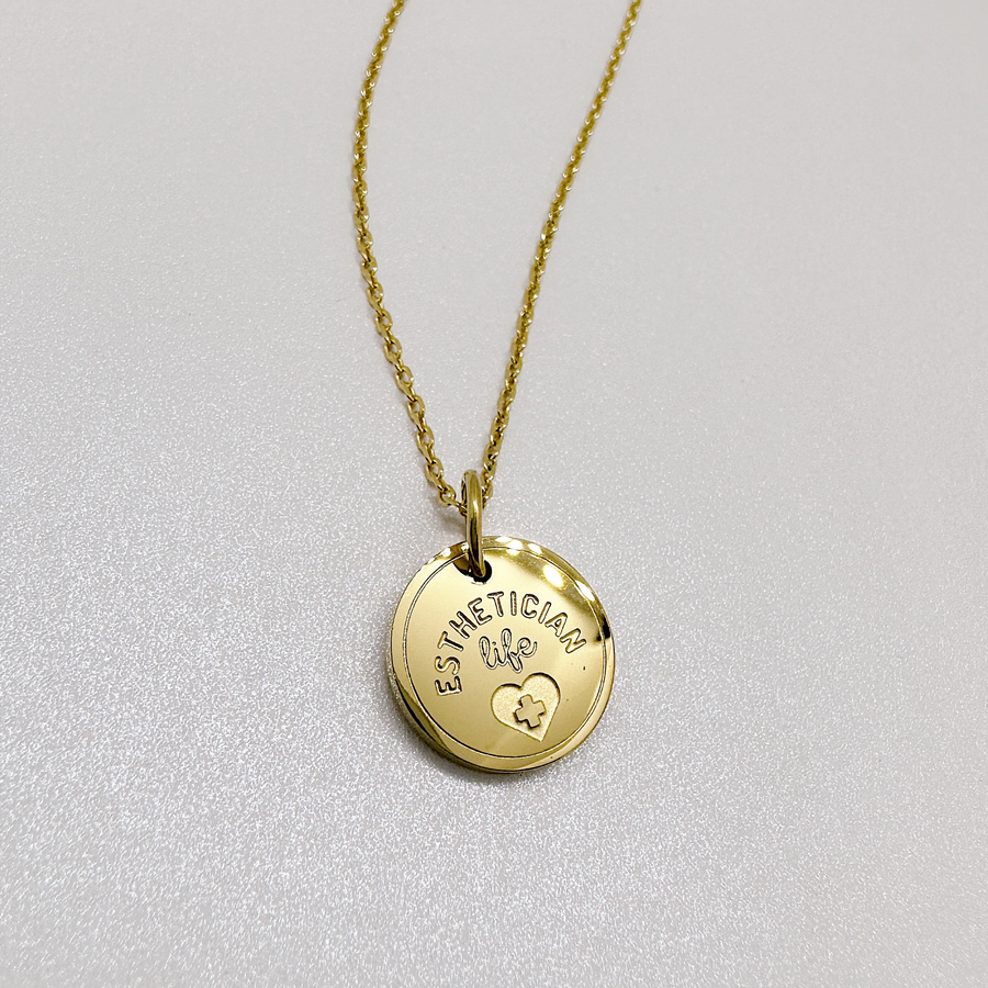 Gold esthetician disc charm necklace.